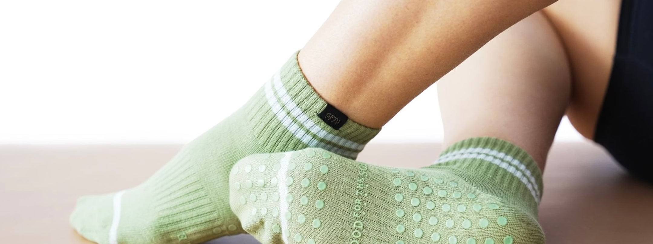 Green socks with white stripes worn by a person on a light background