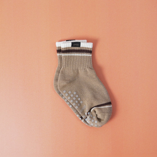 Beige ankle sock with grip dots on a peach background