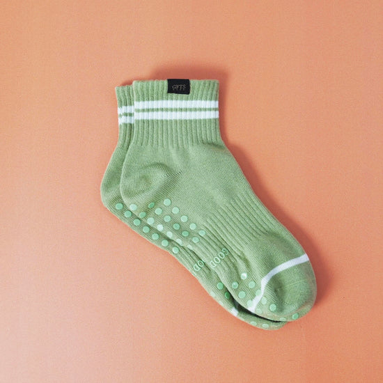 Green ankle sock with white stripes on a beige background