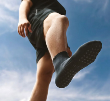 Person wearing black socks with textured sole against a blue sky