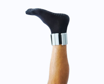 Black sock on a wooden walking stick with silver bands against a white background