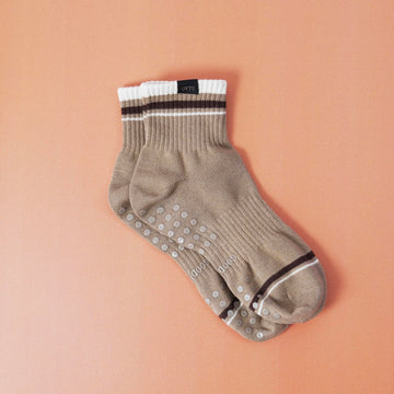 Beige sock with white sole and black stripes on a peach background