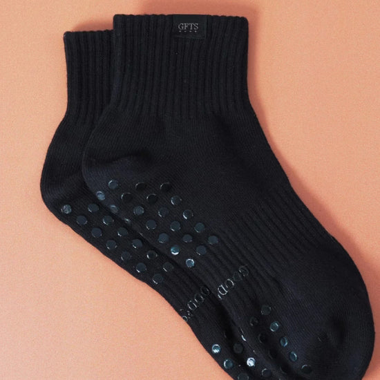 Black ankle socks with non-slip dots on a peach background