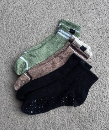 Three pairs of socks in green, brown, and black on a gray surface