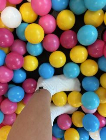 Colorful plastic balls with a person's head peeking out from the center.