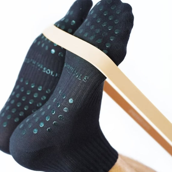 Black socks with green dots worn by a person on a white background